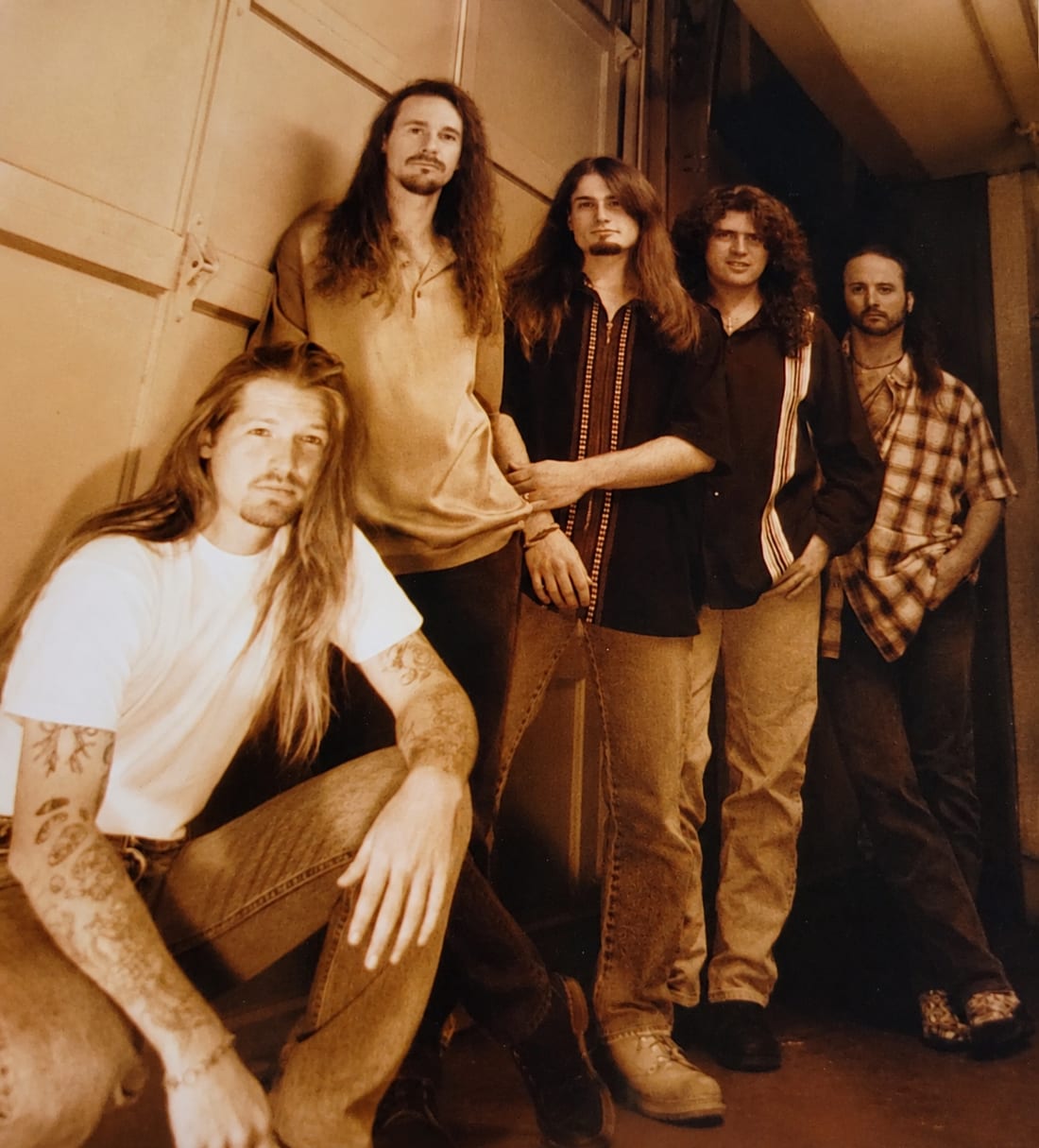 Algebra of Light band photo in sepia, five members posed in front of a garage door.